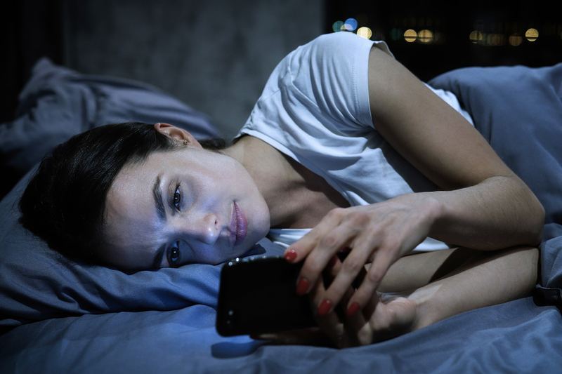 A woman up late in bed, worn out from scrolling dating apps